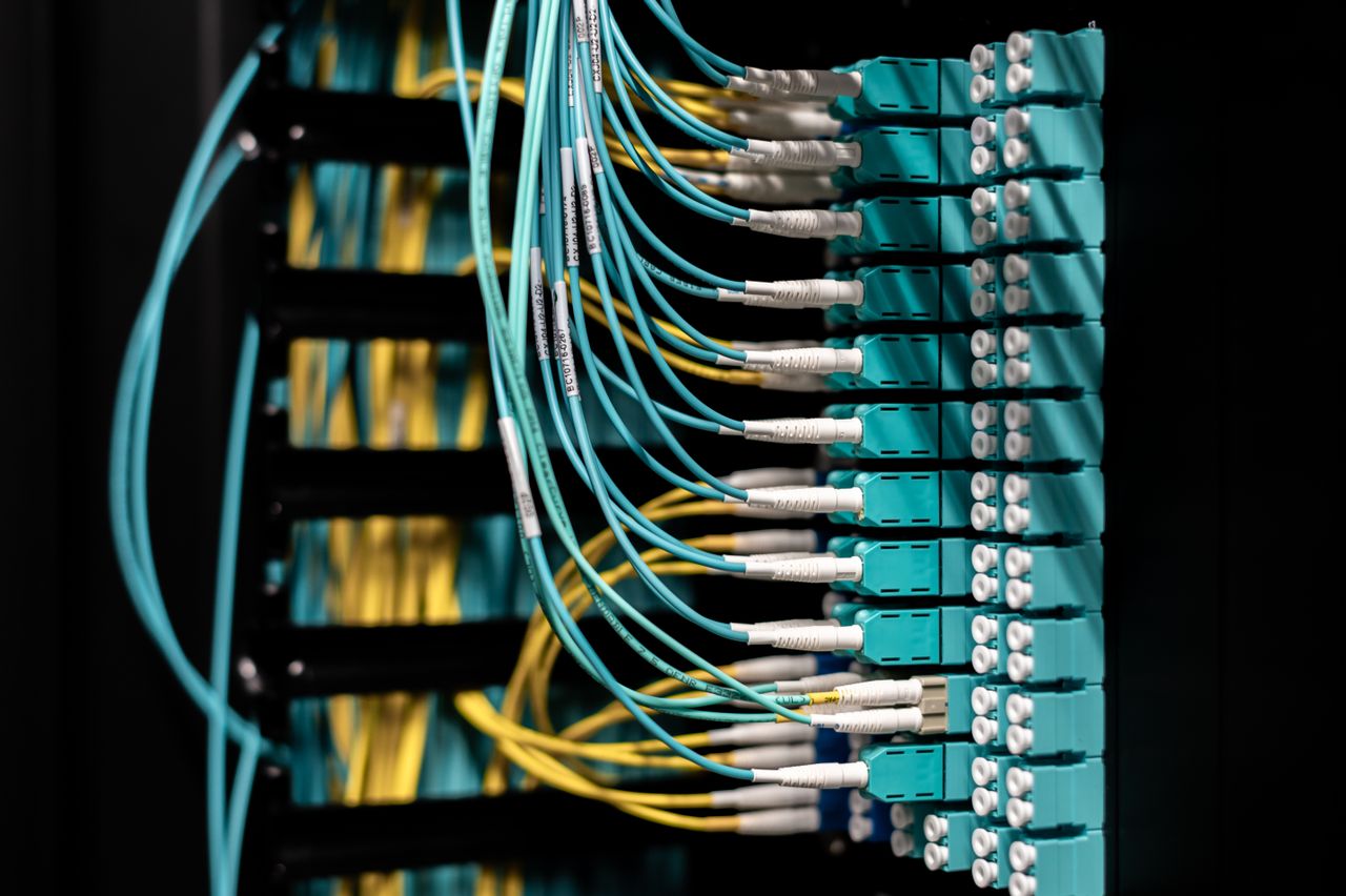 heros-img Closeup of electronic device with colorful wires installed in rows in communications room on blurred background in dark studio inside